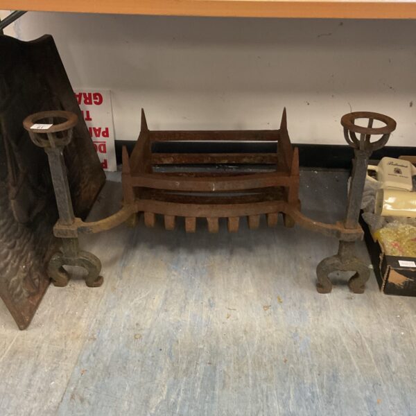 Antique wrought iron fireplace grate with decorative scrollwork.