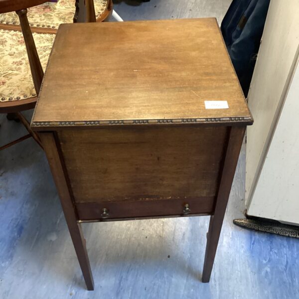 Vintage wooden sewing table with drawer, side view.