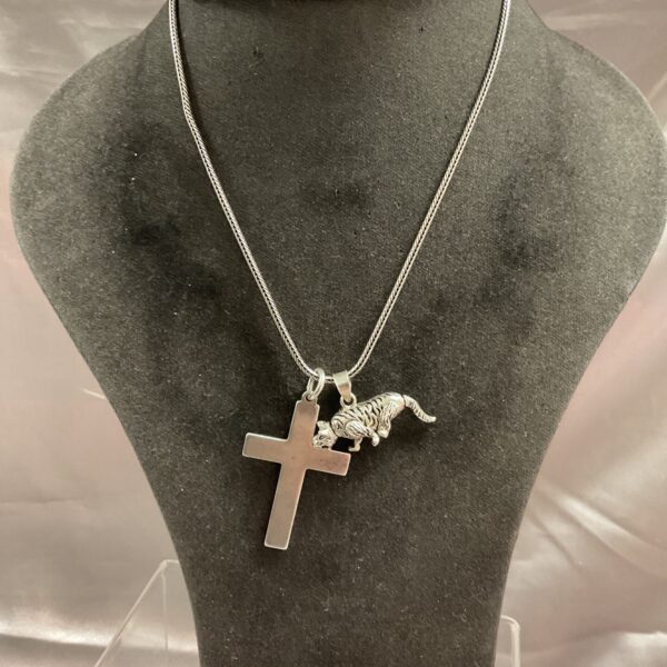 Silver tiger and cross necklace on display, detailed pendant.
