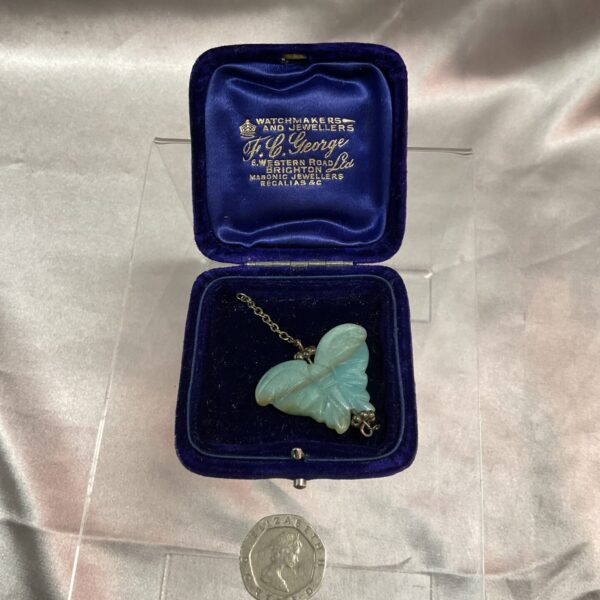 Antique jade butterfly pendant on a chain, detailed carving.