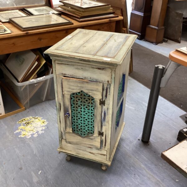 Small distressed wooden cabinet with blue pierced panel.