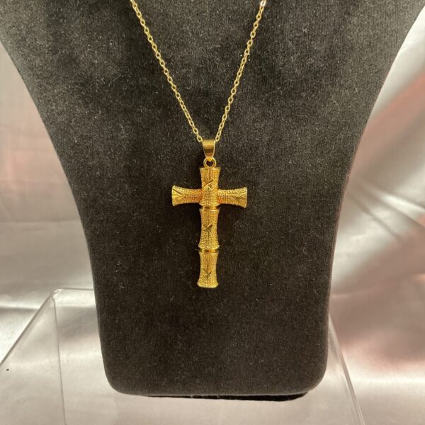 Vintage yellow metal crucifix necklace on a chain.