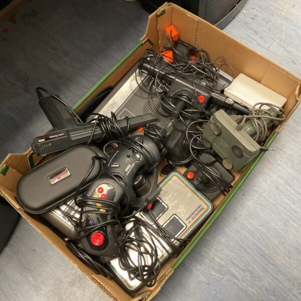 A box of assorted retro gaming controllers and a Nintendo DS.