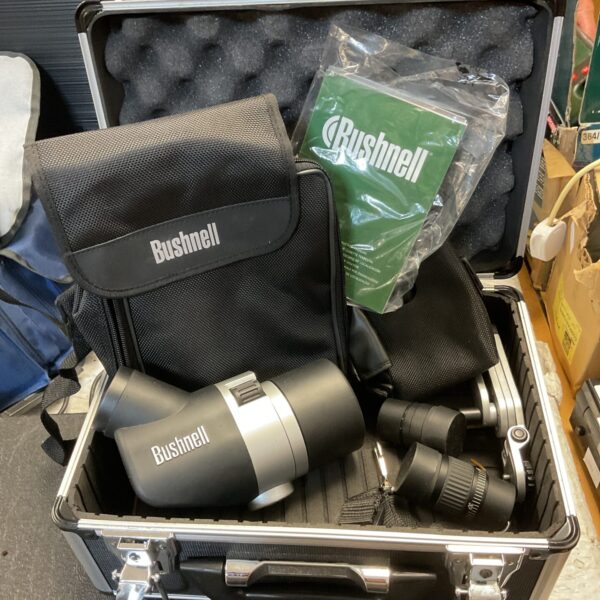 Bushnell spotting scope in a hard carrying case with accessories.