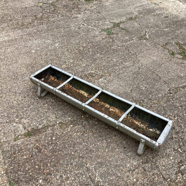 Weathered metal animal feed trough, showing signs of age and use.