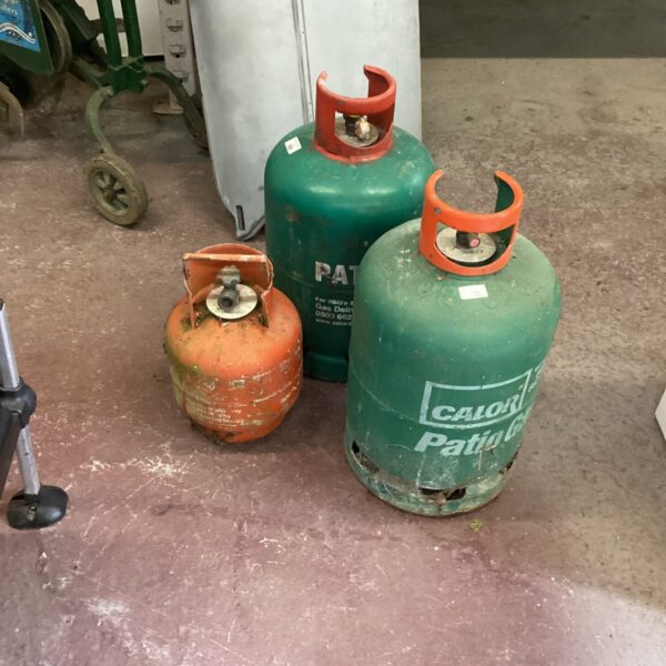 Lot of three used patio gas bottles for outdoor use.