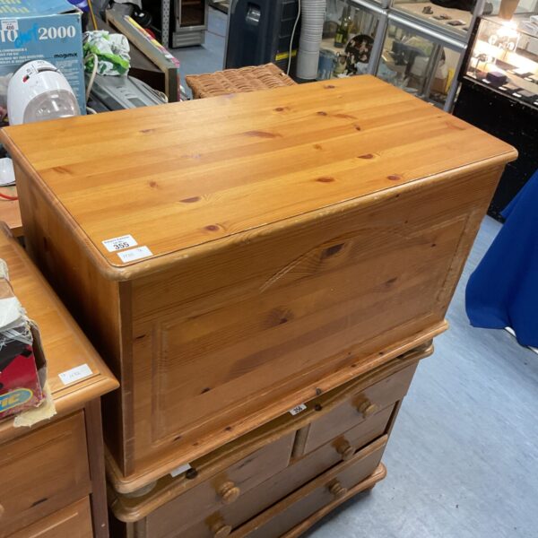 Front view of a small pine chest with lift-top lid.
