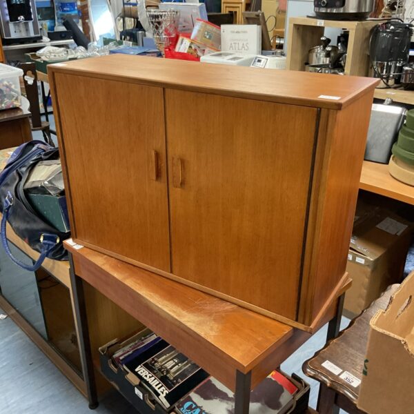 Front view of a mid-century teak cupboard with two doors.