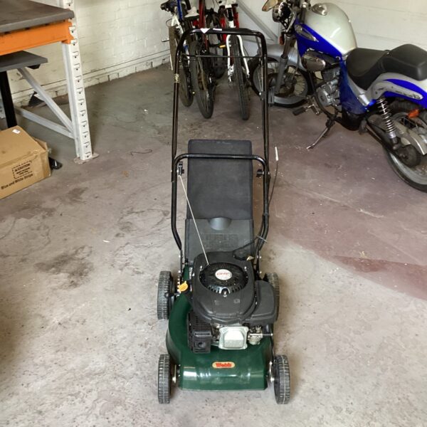 Green Webb petrol lawn mower in a garage setting.