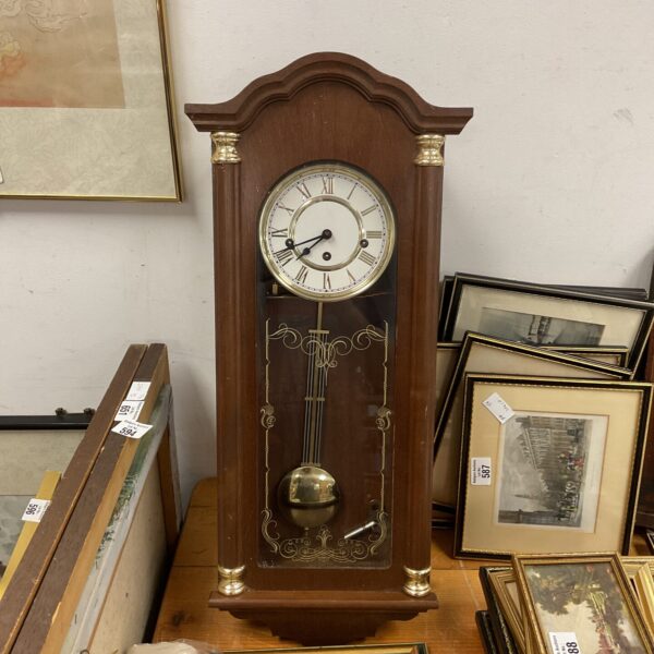 Vintage German wall clock with pendulum and Roman numerals.