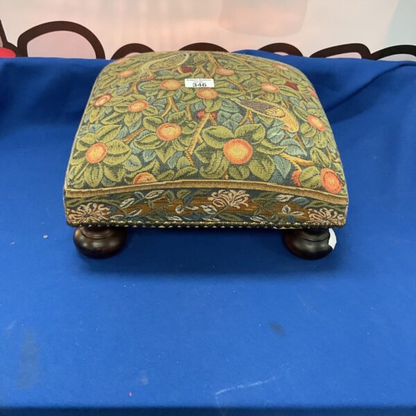 Vintage floral footstool with detailed tapestry upholstery and turned legs.