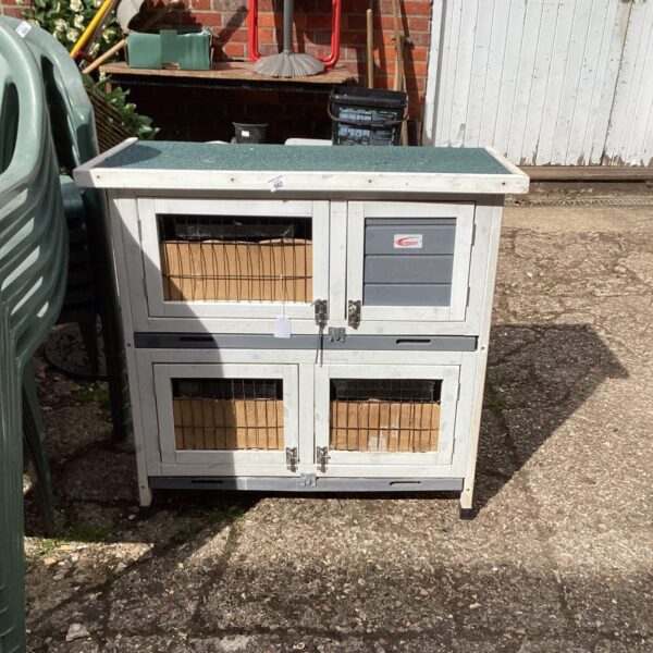 Wooden rabbit hutch in a garden setting, providing outdoor animal housing.