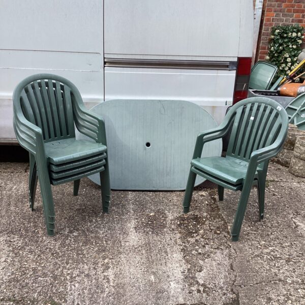 Plastic garden table and six chairs in a garden setting.