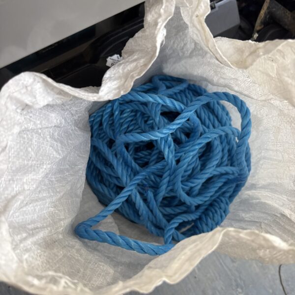 Large blue nylon rope coiled for storage, showing signs of use.