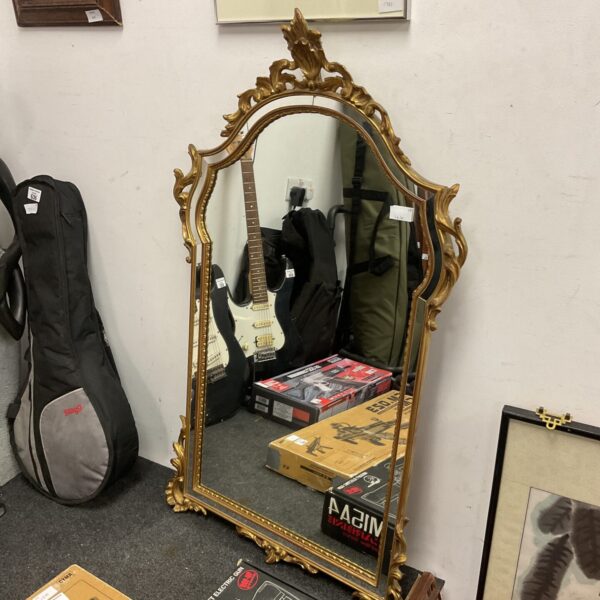 Ornate gilt framed French boudoir mirror with detailed carvings.