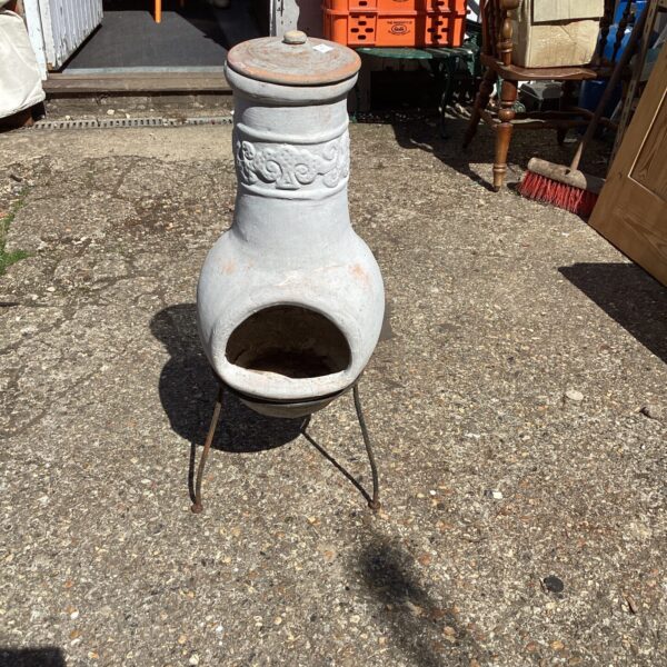 Rustic terracotta garden chiminea with three legs.