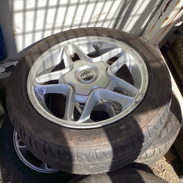 Silver alloy wheel for classic Mini, showing signs of wear.