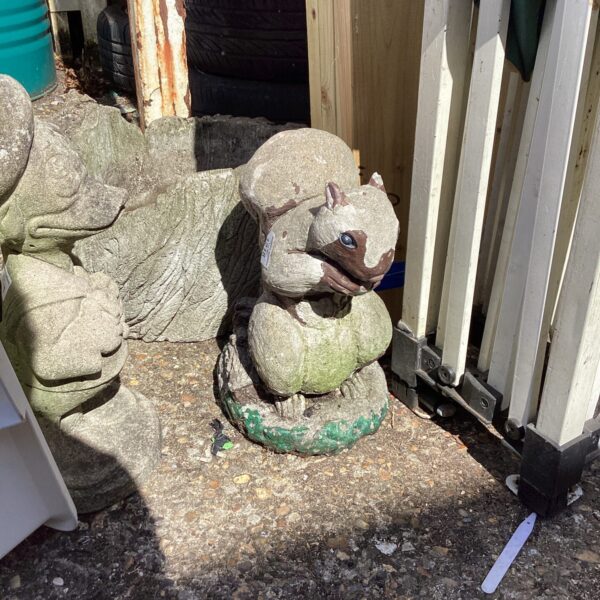 Detailed concrete garden squirrel ornament in a garden setting.