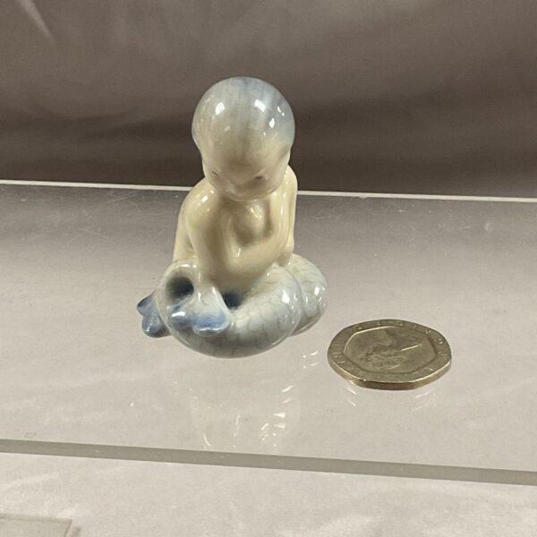 Vintage Royal Copenhagen mermaid figurine on a white surface.