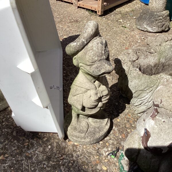 Vintage Disney Donald Duck garden ornament in a weathered garden.