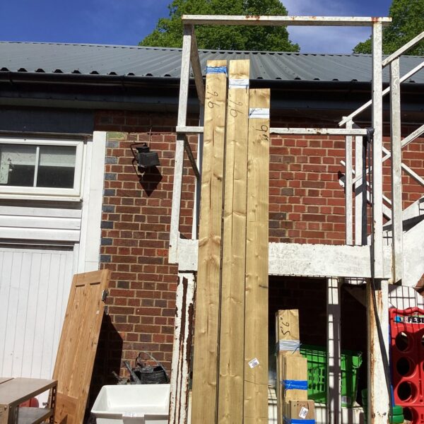 Three bundles of 9’6” timber stacked near a building.
