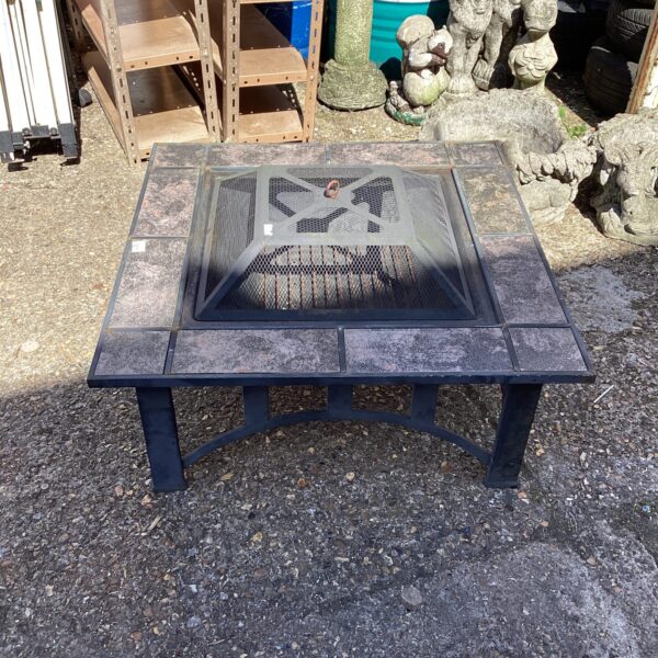Tile-topped garden fire pit with metal frame and central fire bowl.