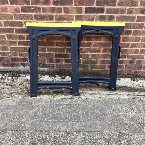 Pair of black plastic folding trestles for work or events.