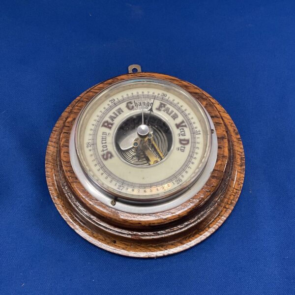 Antique oak wall barometer displaying rain and fair weather indicators.