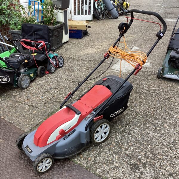 Red and black Cobra electric lawn mower in a garden setting.