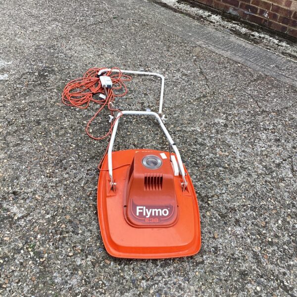 Vintage orange Flymo hover mower for garden maintenance.