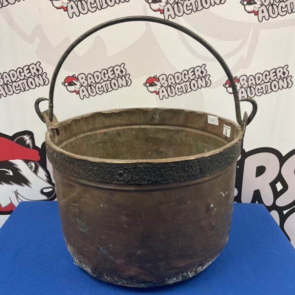 Large antique copper cauldron with arched handles, front view.