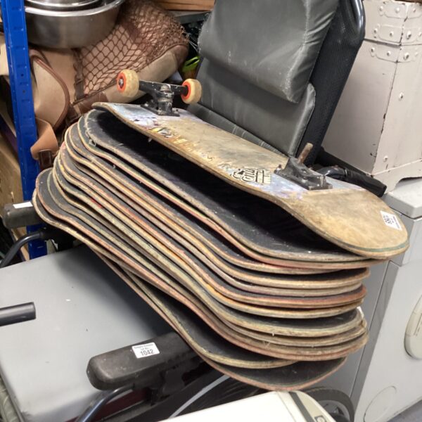 Stack of used skateboard planks in a mixed lot.