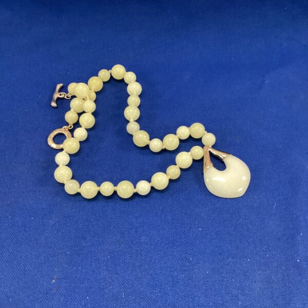 Close-up of a chunky jade bead necklace with a pendant.