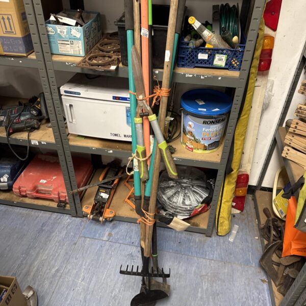 Bundle of used garden tools including a spade and rake.