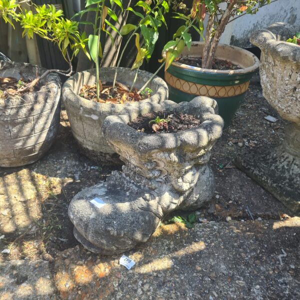 Weathered stone shoe garden ornament with plants.