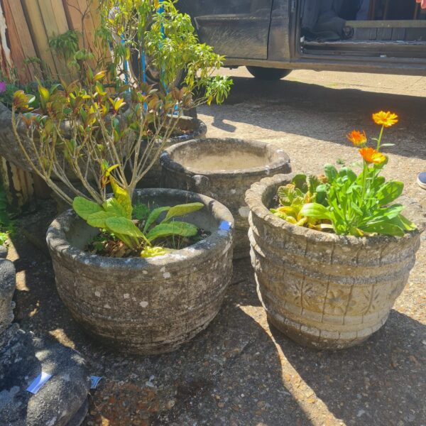 Pair of weathered stone garden planters with plants.