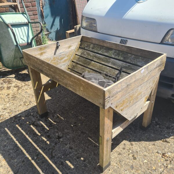 Rustic wooden planter trough in a garden setting.