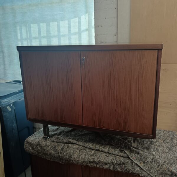 Vintage teak storage cabinet with chrome legs and locking doors.