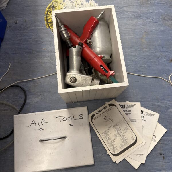 Assorted air tools in a wooden box, including a spray gun and chisel.