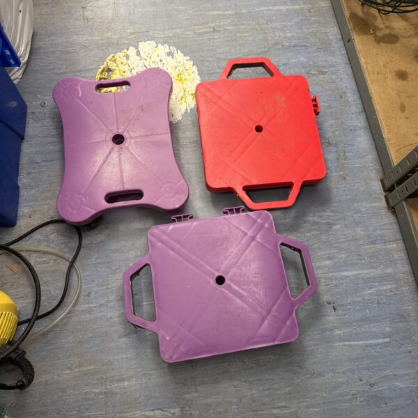 Lot of three heavy duty plastic dollies for moving equipment.