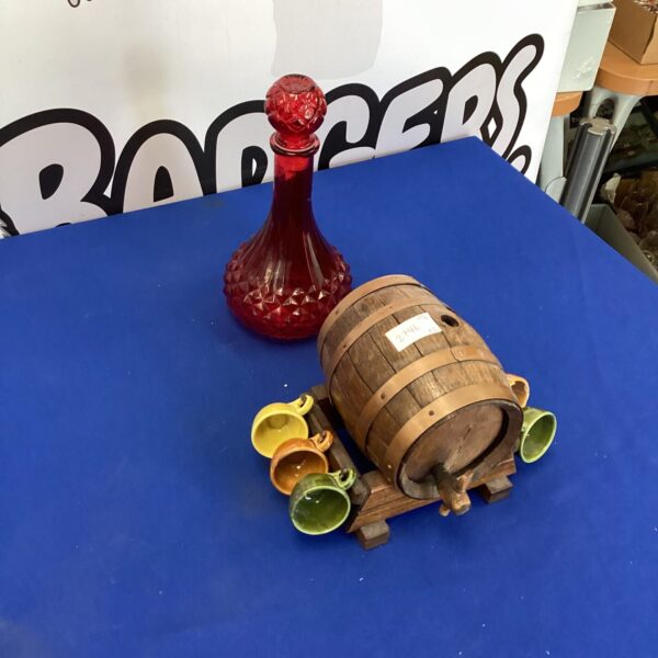 Vintage sherry barrel and red glass decanter set for display.