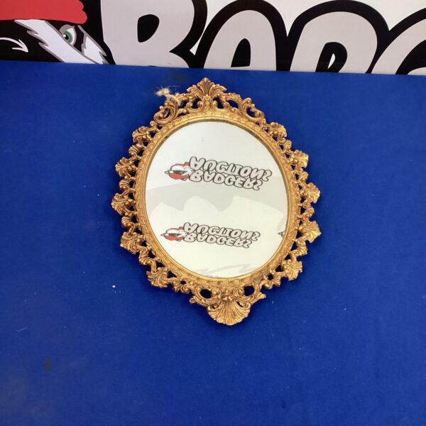 Small vintage gold mirror with decorative frame.