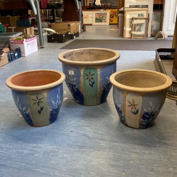 Set of three large ceramic plant pots with floral design.