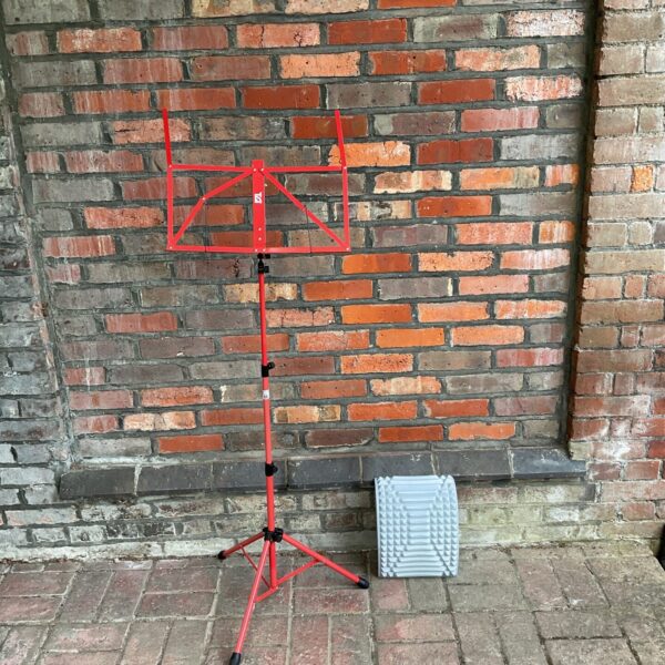 Red sheet music stand with violinist foot rest, portable musician's equipment.