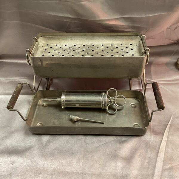 Antique field medical sterilizer with large syringe for surgical instruments.