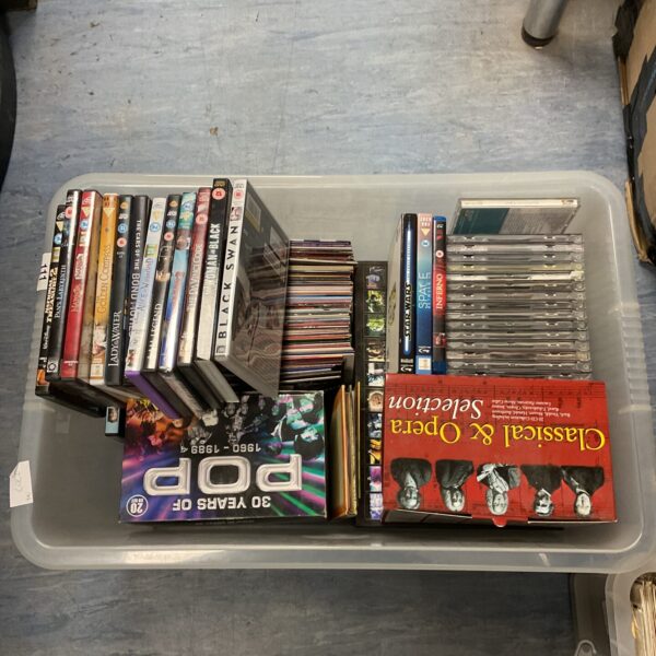 Plastic container filled with a diverse lot of DVDs and music CDs.