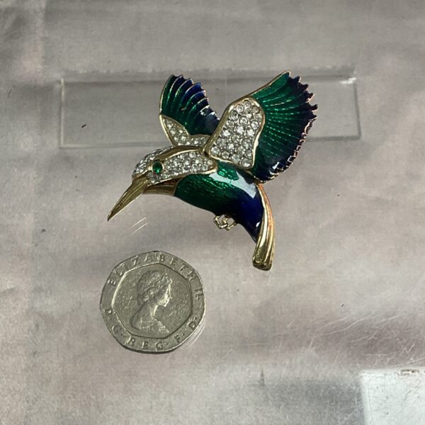 Close-up of a vintage enamel kingfisher brooch with crystal eyes.