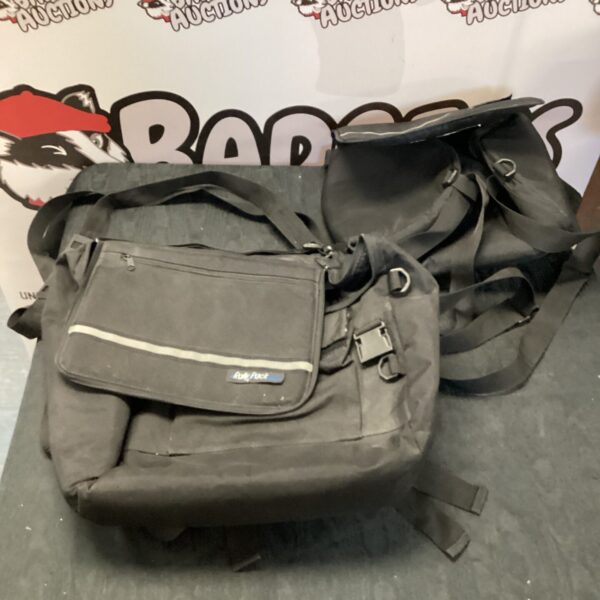 Black motorcycle pannier bags showing wear and tear.