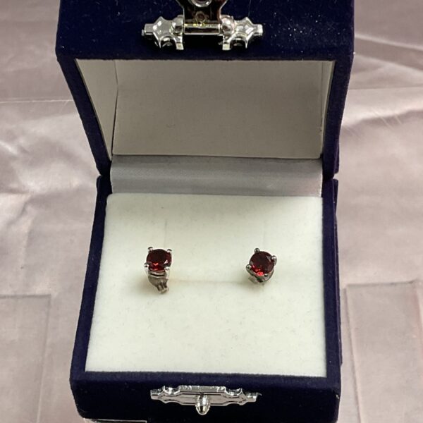 Close-up of red garnet stud earrings in a silver setting.