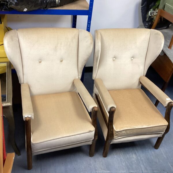 Pair of vintage cream wingback chairs with wooden frames.